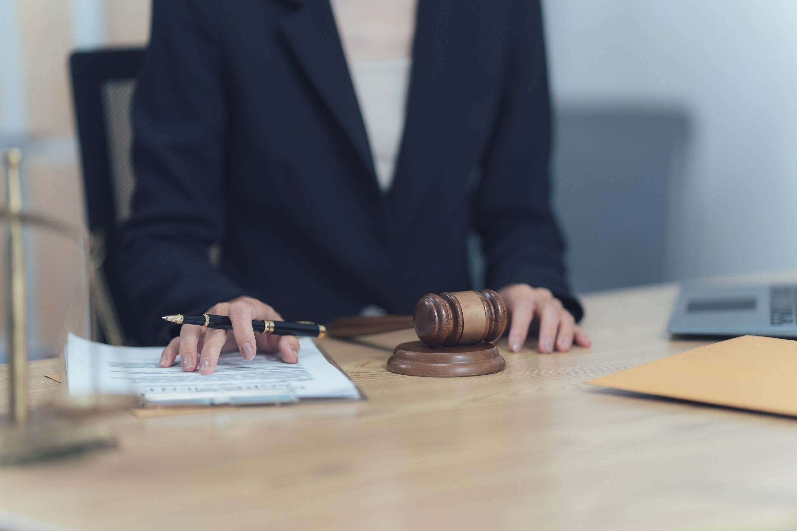 Law and Justice: A close-up shot of a lawyer reviewing legal documents, with a gavel and a scale of justice in the frame, highlighting the seriousness and significance of legal proceedings.