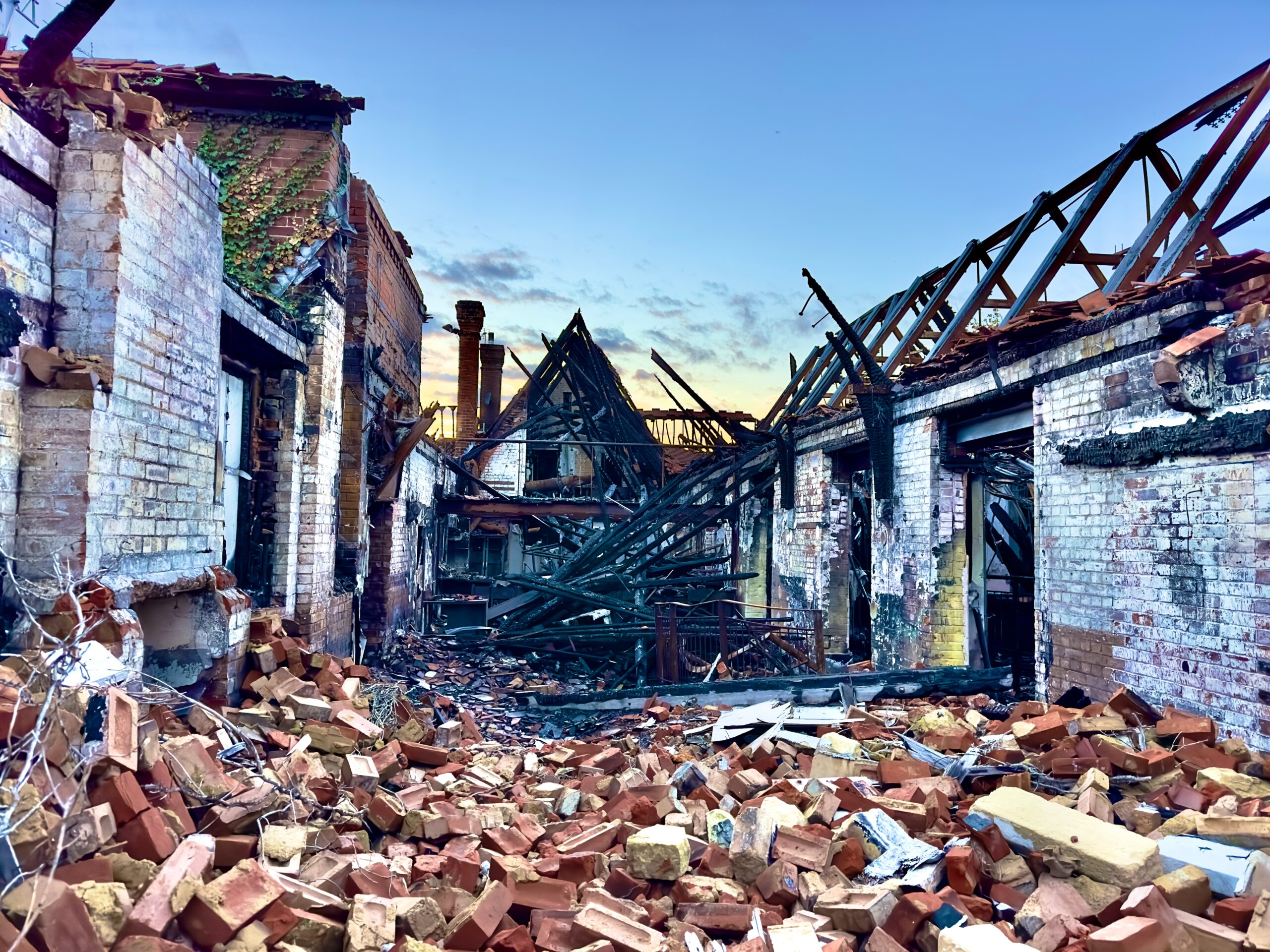 The charred ruins of a house destroyed by fire with rubble on the ground.